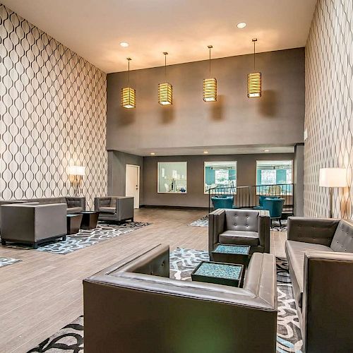 A modern lounge area with patterned wallpaper, sofas, seating, lamps, and hanging lights. The design is sleek and contemporary, featuring teal accents.
